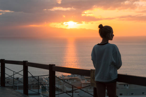 istock Young woman standing at view point and looking at sea while sunset 912020454