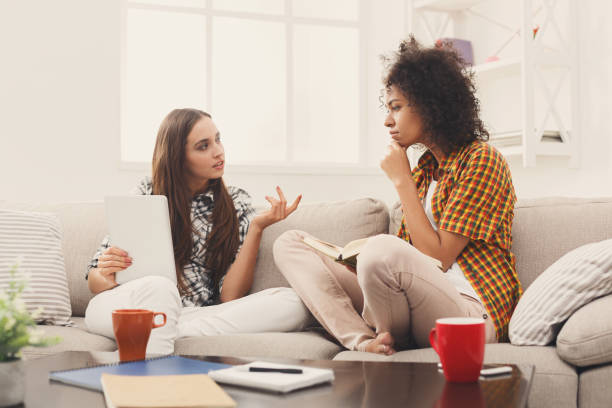 istock Two female friends reading books at home 912028834