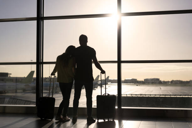 Couple waiting for flight in airport Silhouette of couple waiting for flight in airport malay couple full body stock pictures, royalty-free photos & images
