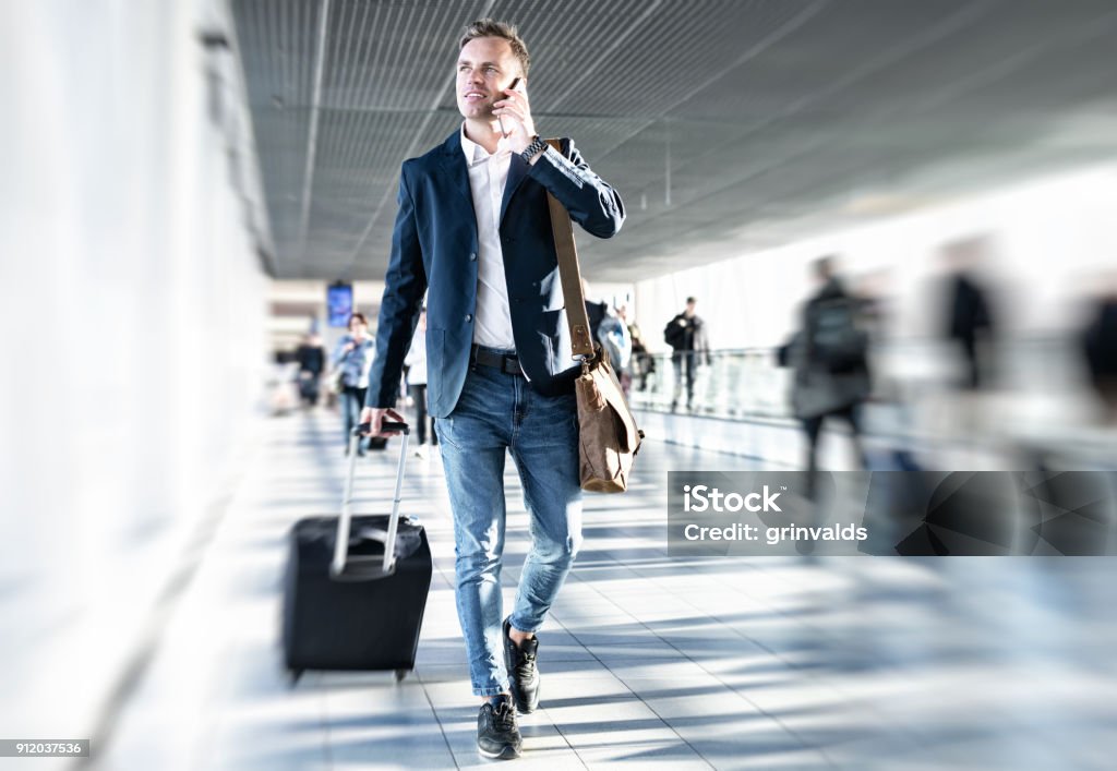 Businessman walking in airport Businessman talking on phone and rushing in airport, blurred background Airport Stock Photo