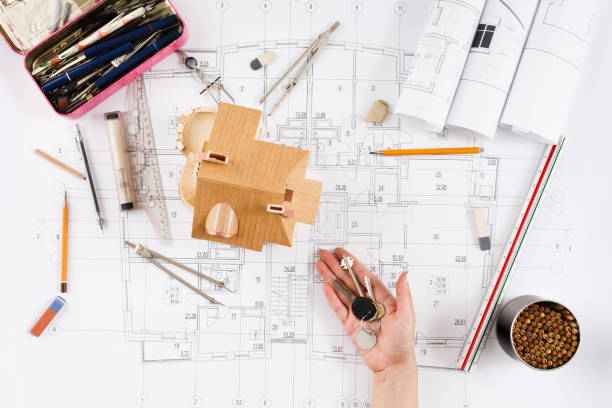 Architect holding keys at house model in office