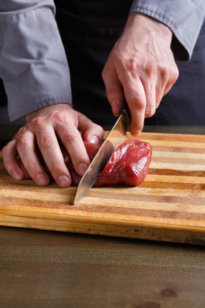 istock Chef cutting filet mignon on wooden board at restaurant kitchen 912061414