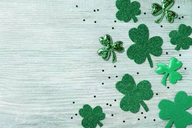 Photo of Saint Patricks Day background with green shamrock on white rustic board top view.