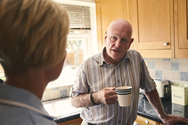 istock Retired man talking with female nurse in kitchen 912072012