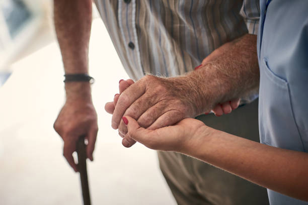 female nurse supporting senior man to walk - holding hands human hand senior adult consoling imagens e fotografias de stock