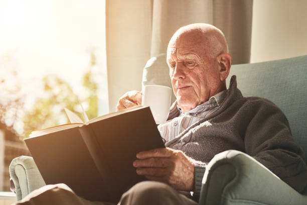 istock Elderly man reading a book at home 912073240