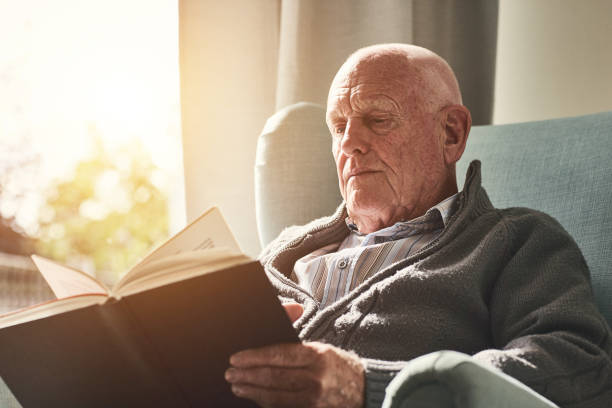 istock Senior man reading a book at home 912073252