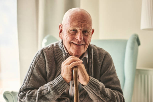 Happy senior man sitting at home Portrait of happy senior man sitting at home with walking stock and smiling senior men stock pictures, royalty-free photos & images