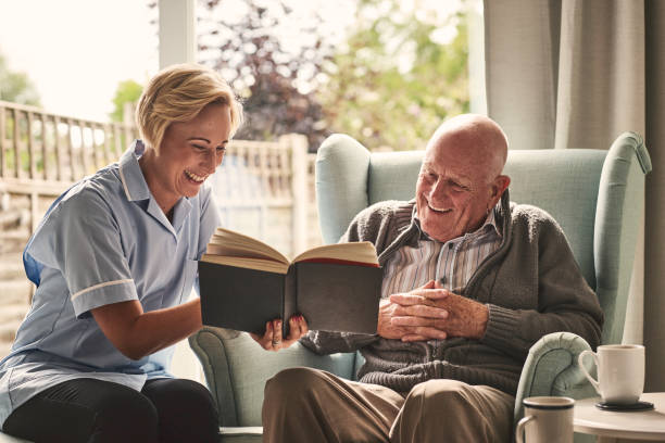 istock Smiling female carer reading book for senior patient 912073312