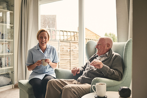 Senior hombre y cuidador hembra disfrutando de café en casa photo