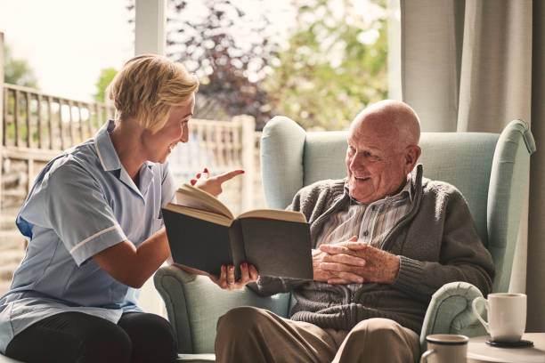 istock Happy senior man with carer reading a book 912073332
