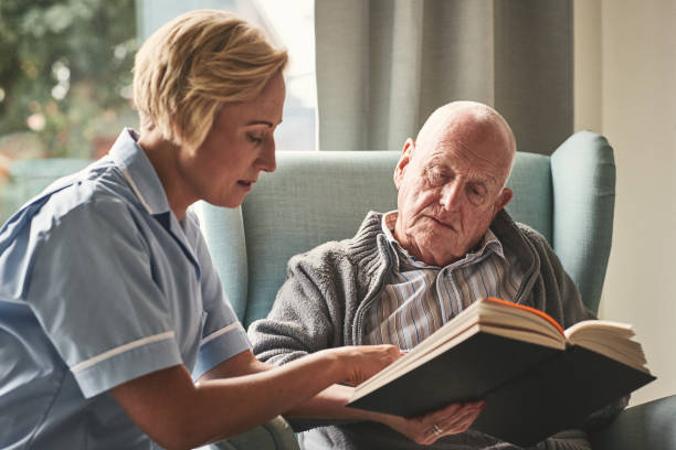 istock Elderly man with carer reading a book 912073334