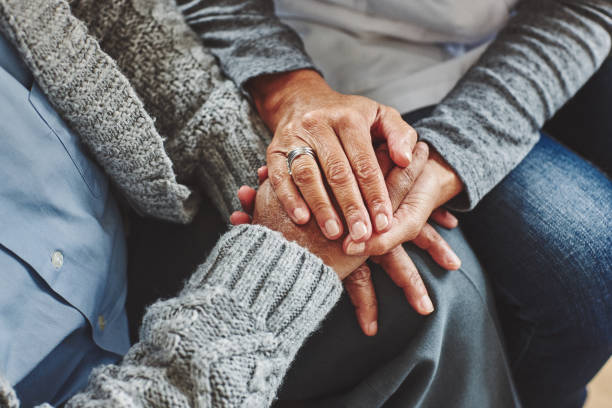 Female carer holding hands of senior man Female healthcare worker holding hands of senior man at care home, focus on hands. guidance support stock pictures, royalty-free photos & images