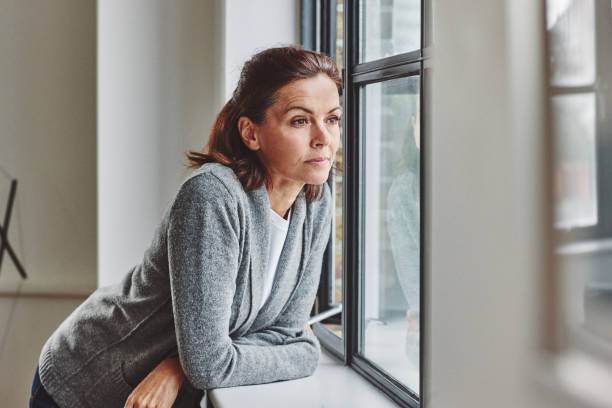 Thoughtful senior woman standing by the window