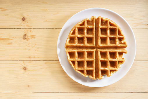 fresh baked waffle in a pattern on wooden background, top view