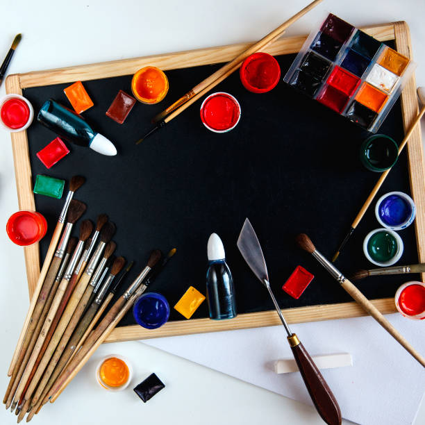 istock Drawing accessories, paints and brushes lie on an empty black chalkboard. The concept of creativity and painting. Overhead still life with copy space. 912090704