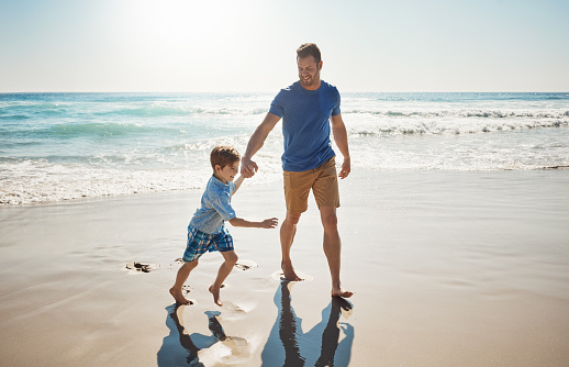 Shot of a father and his little son bonding together at the beach