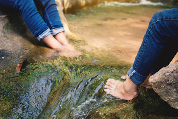istock Low Section Of People Sitting In Rocky Stream 912101778