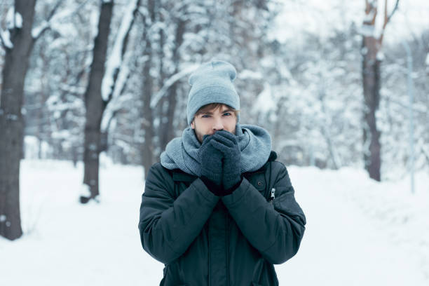 istock portrait of young man warming hands up while walking in snowy park 912107894