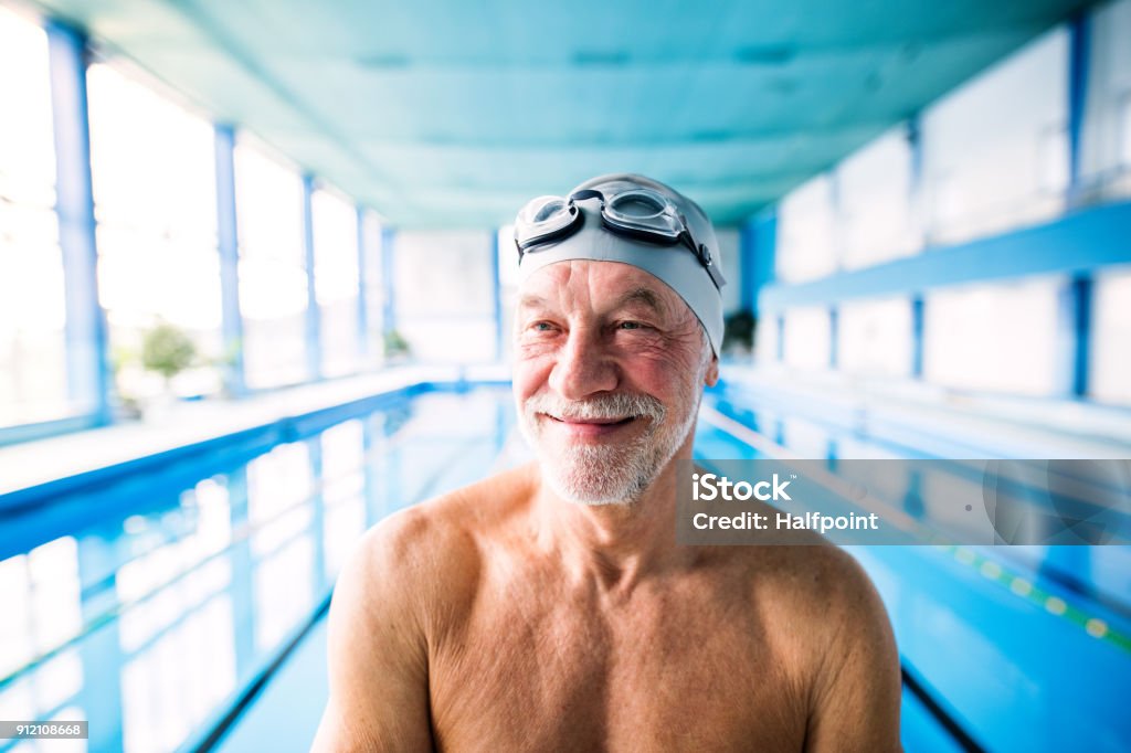 Senior man in an indoor swimming pool. Senior man in an indoor swimming pool. Active pensioner enjoying sport. Senior Adult Stock Photo