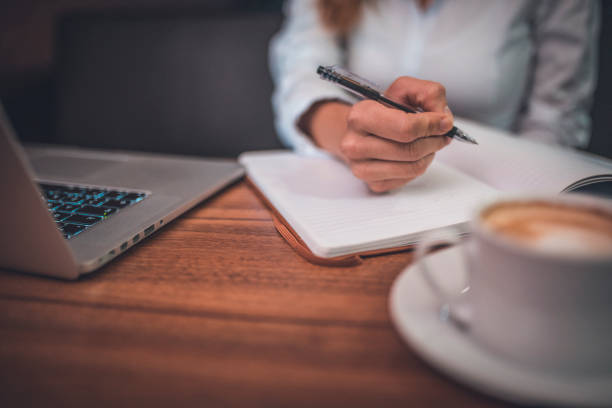 istock Businesswoman using laptop and writing in a coffee shop 912112618