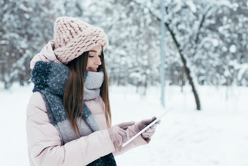 side view of smiling young woman with tablet in winter park