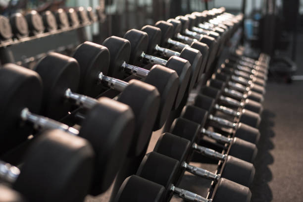 Dumbbells on Stand in Gym Background image of dumbbells in row on equipment stand in modern gym, copy space dumbbell stock pictures, royalty-free photos & images