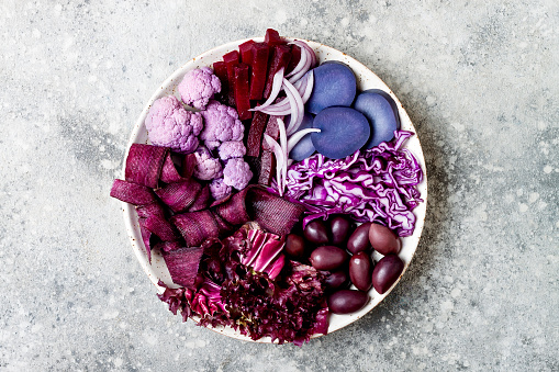 Purple Buddha bowl with spiral carrots, cauliflower, beet, onion, potato, shredded red cabbage, radicchio salad, kalamata olives. Vegan detox veggie bowl