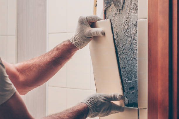 Worker breaks the remnants of tiles off the wall