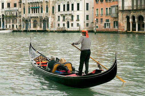 VENICE, ITALY - SEPTEMBER 26, 2021: A gondolier steers his boat into moorage just as raindrops start to fall on Venice.