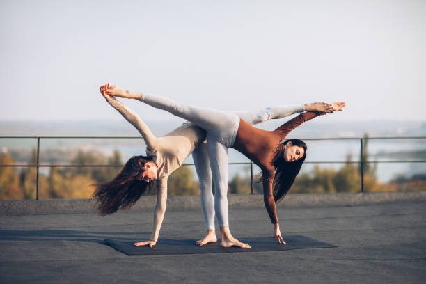 two beautiful women doing yoga asana ardha chandrasana - concentration flexibility full length healthy lifestyle imagens e fotografias de stock
