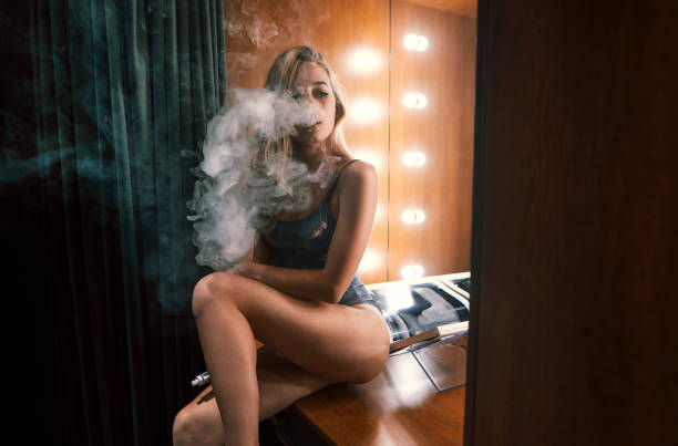 istock Young beautiful blond woman smoking, vaping e-cigarette, vape mod. Vapor concept 912120498