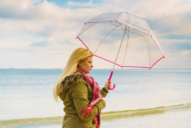 istock Woman standing with transparent umbrella on beach 912120668