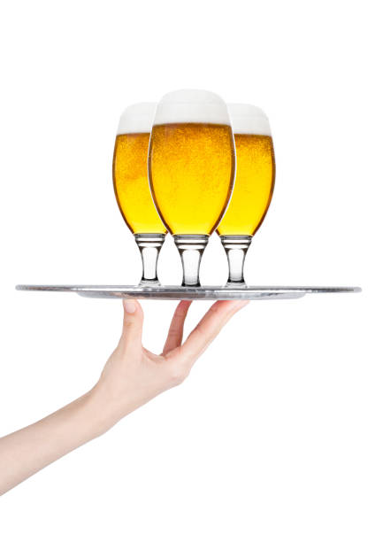 Hand holds tray with lager beer glasses with foam and dew isolated on white background