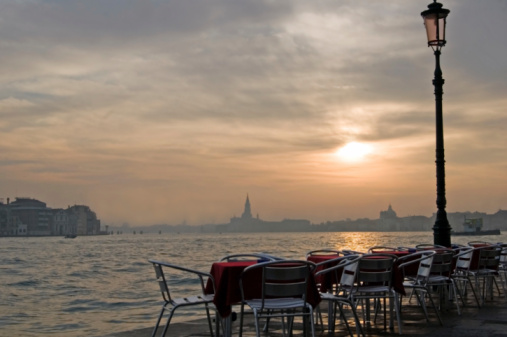 Empty Cafe Tables with red table cloths at Sunrise in Venice.