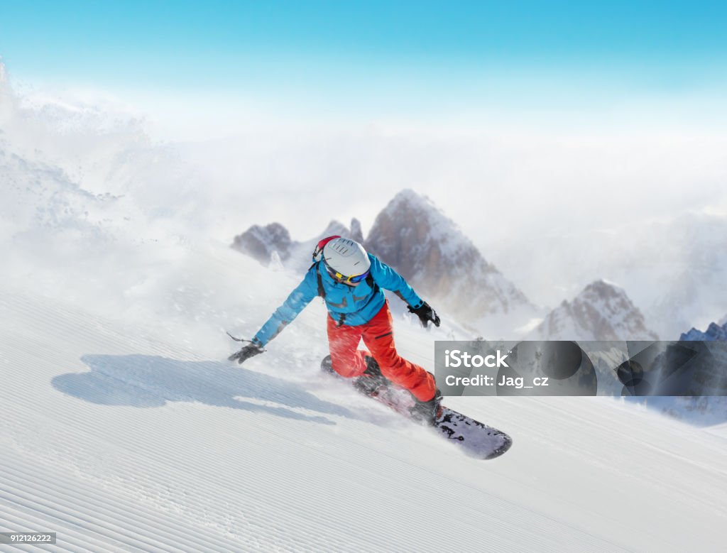 Young man snowboarder running downhill in Alps Young man snowboarder running downhill, Alpine mountains. Winter sport and recreation, leasure outdoor activities. Snowboarding Stock Photo