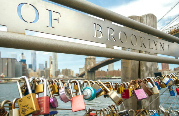Closeup of love locks in fence with Brooklyn Bridge of New York City on the background