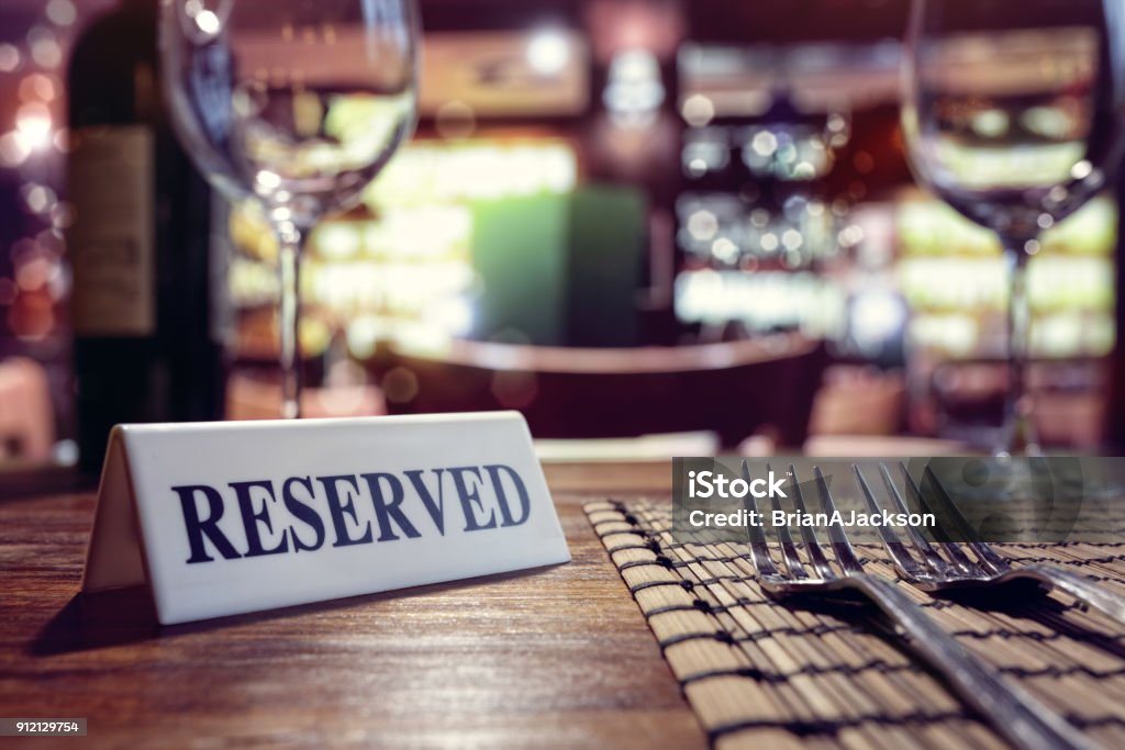 Reserved sign on restaurant table with bar background Restaurant reserved table sign with places setting and wine glasses ready for a party Restaurant Stock Photo