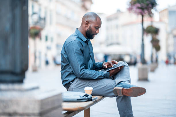 istock Businessman sitting on a bench and using digital tablet in the city 912130014