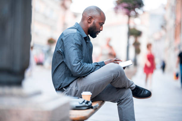 Businessman sitting on a bench and using digital tablet in the city