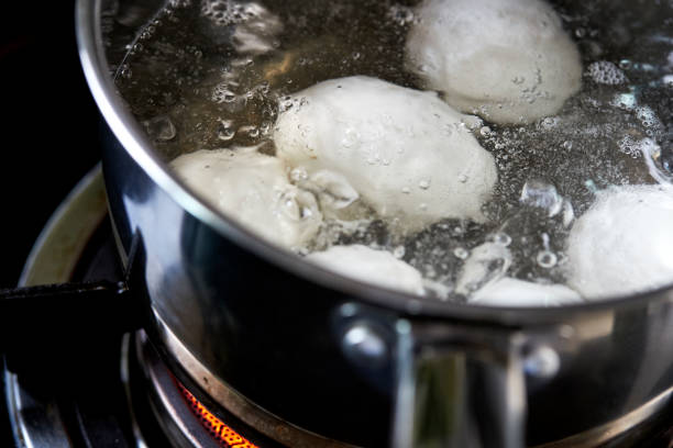 Closeup of white eggs boiling in pot of hot water, made Easter eggs