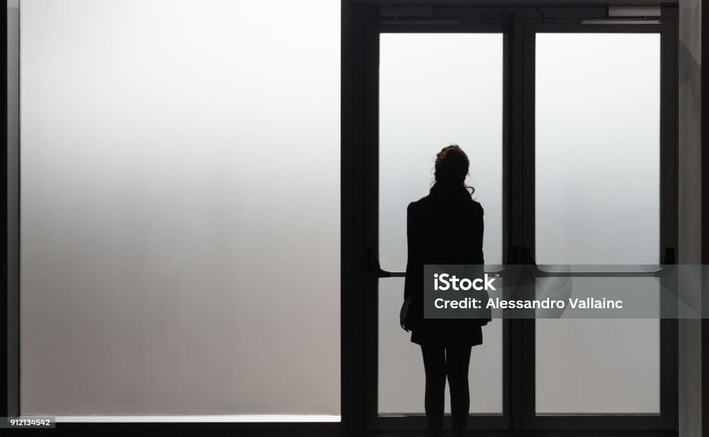 Femme déprimée en attente devant une porte en verre dans une salle blanche prête à réagir - maladie - Abuse - phobie Concept - Photo de Mauvais traitement libre de droits