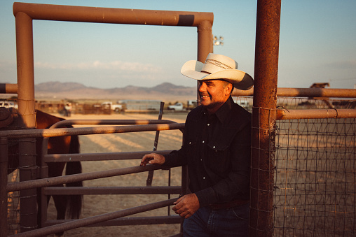 Cowboy opens the gate of Rodeo Arena in the morning