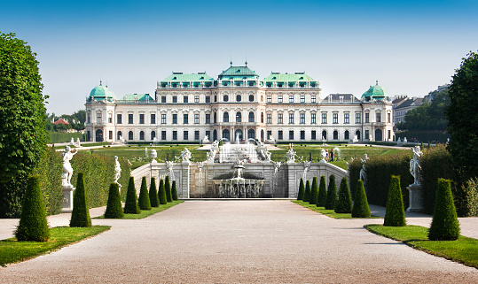 Vienna, Austria - August 12, 2022: Back view of the famous Schonbrunn palace in Austria, seen from a public accessible garden on a sunny day with blue sky and contrasty clouds. Austrian landmark view and its capital city skyline