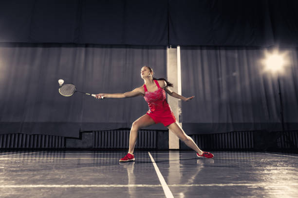 jovem mulher jogando badminton no ginásio - badminton school gymnasium shuttlecock sport - fotografias e filmes do acervo