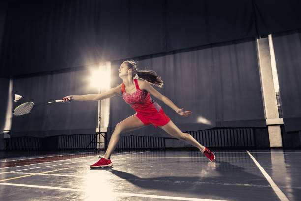istock Young woman playing badminton at gym 912146170