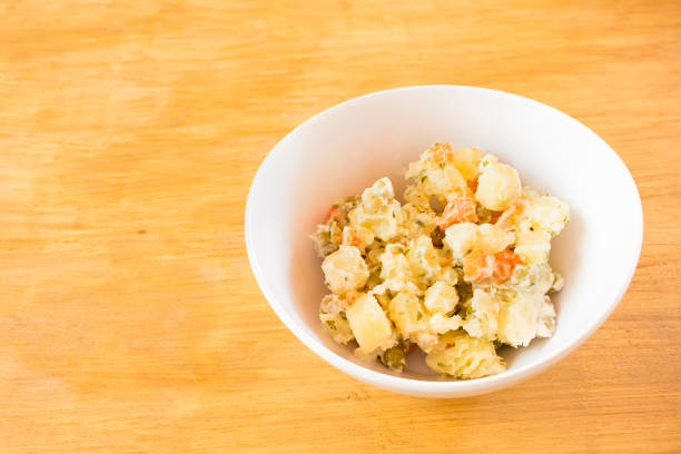 Potato salad in a white bowl on a wood.