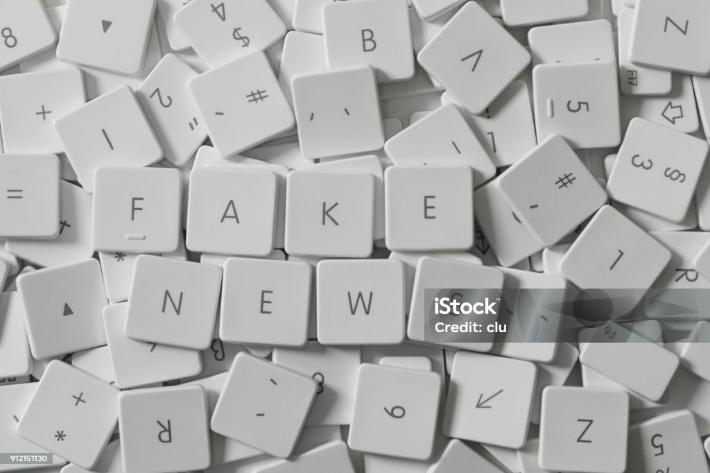 Text FAKE NEWS as keyboard letters lying on a sea of old keyboard letters Artificial Stock Photo