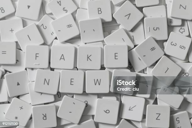 Text Fake News As Keyboard Letters Lying On A Sea Of Old Keyboard Letters Stock Photo - Download Image Now