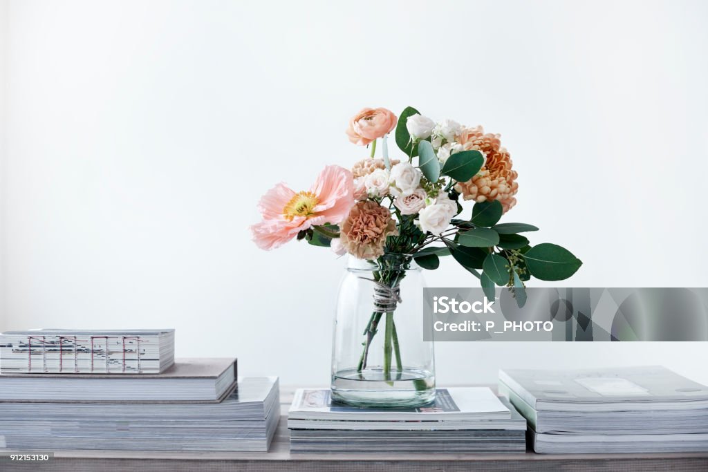 pastel cut flowers in a glass vase bouquet of poppies ranunculus eucalyptus chrysanthemums roses carnations Vase Stock Photo